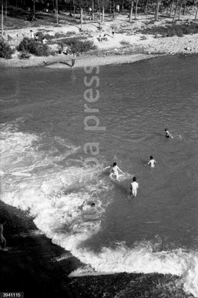 MADRID, ESPAÑA - 16 DE ABRIL DE 1960: Un grupo de niños se bañan en un río junto a una presa a las afueras de Madrid.