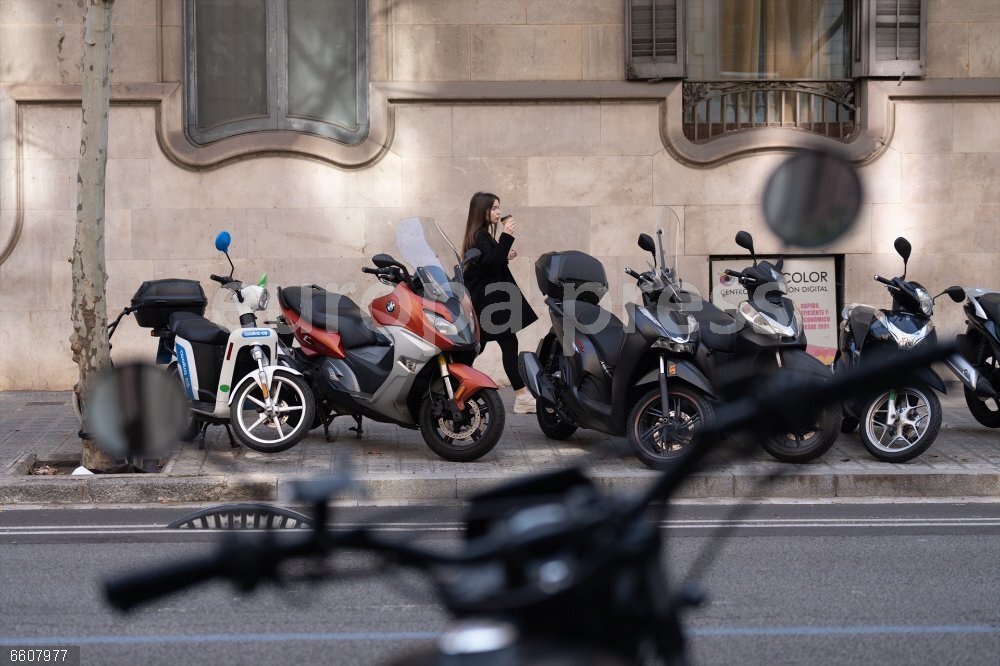 El Ayuntamiento de Barcelona expande la prohibición de aparcar motos en la acera con sanciones de hasta 100 euros Una mujer camina entre varias motos aparcadas en la acera, a 27 de marzo de 2025, en Barcelona, Catalunya (España). La campaña, que se extenderá durante los próximos meses, contempla la instalación de señales de prohibición en los accesos a un total de 325 equipamientos, incluyendo escuelas y hospitales. Esta iniciativa se enmarca dentro de la modificación de la Ordenanza de Circulación, Vianantes y Vehículos (OCVV), que entró en vigor el pasado 1 de febrero y busca proteger a los usuarios más vulnerables del espacio público.