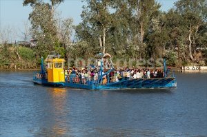 La barcaza de Coria del Río se llena de peregrinos para cruzar el Guadalquivir camino de la Aldea Almonteña
